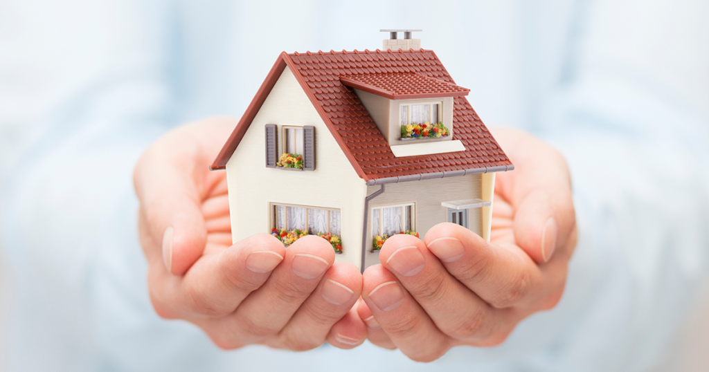 Hands holding miniature model of a home.